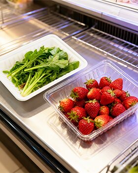 Fresh strawberries and greens in clamshell packaging on a supermarket shelf