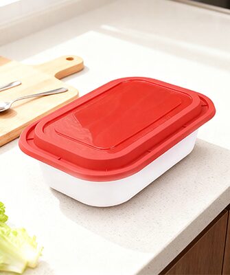 Deli container with red lid on a kitchen counter