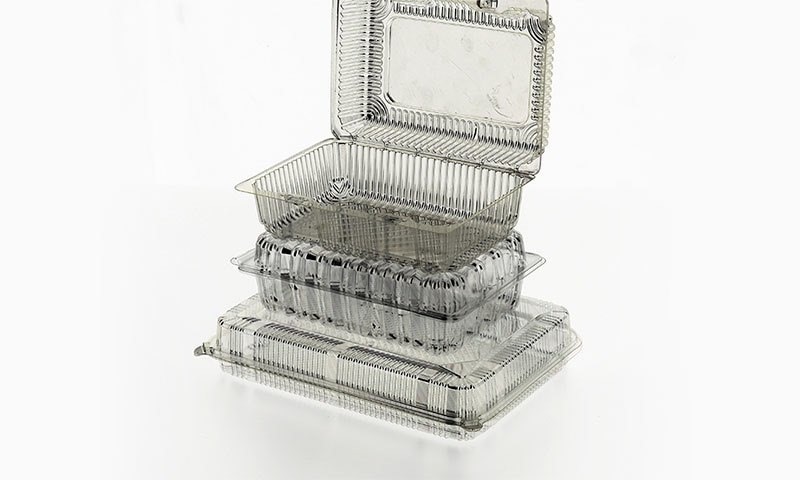 Clear PET hinged fruit clamshell containers, stacked, on white background