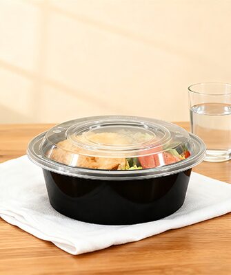 Black round bakery box with sandwich and glass of water