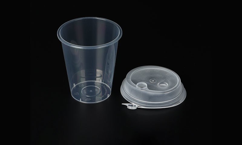 Clear PET plastic cold cups with dome lids on dark background
